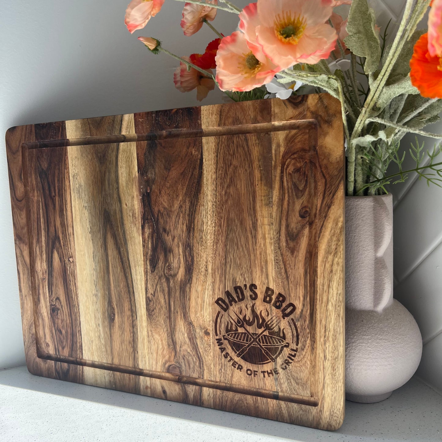 Wooden cutting board with 'Dad's BBQ' engraving.