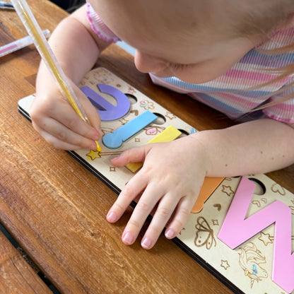 Child playing with a wooden letter puzzle snd colouring in pictures