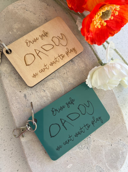 Two keychains with 'DADDY' engraved on them, one wooden and one acrylic teal personalised 