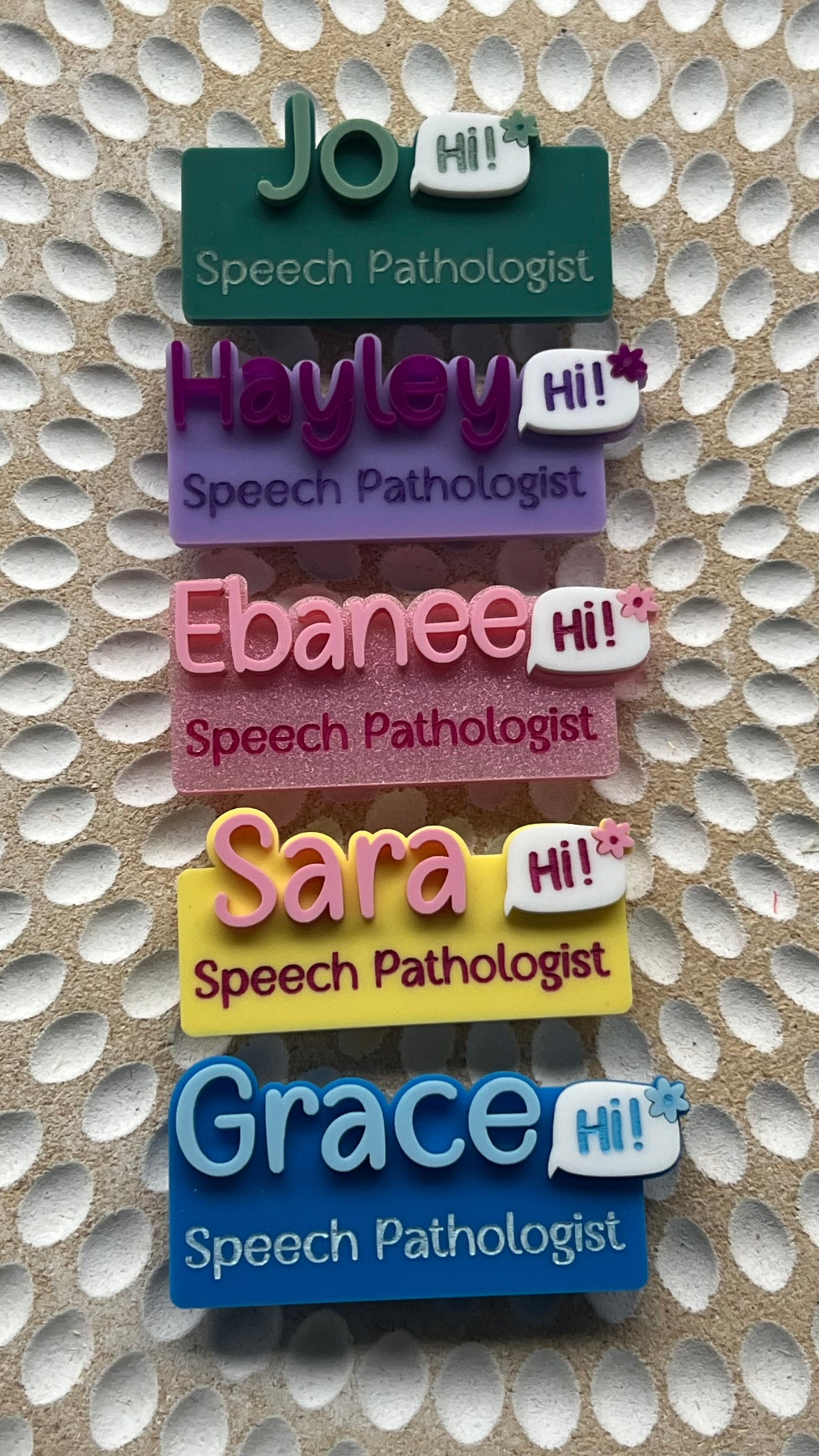 Set of colorful name tags for speech pathologists on a textured background