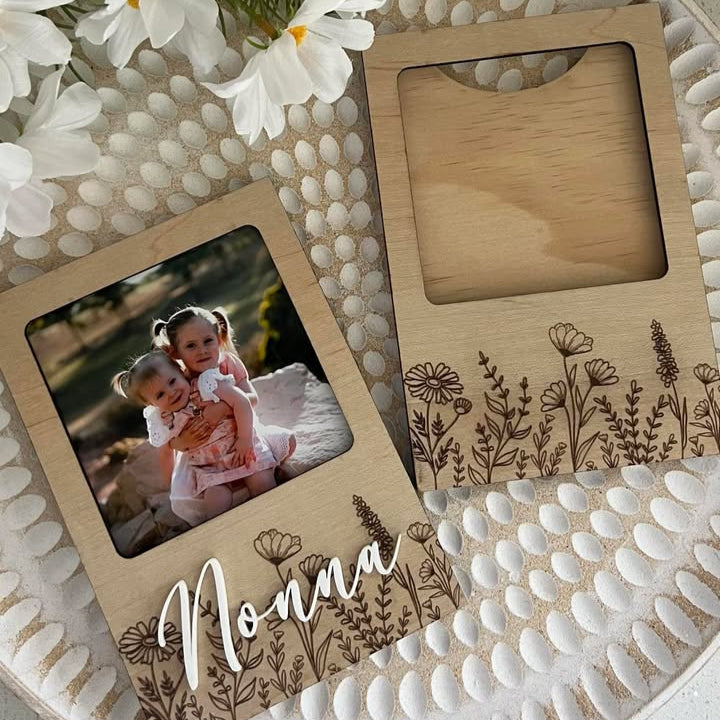 A personalized wooden fridge magnet with floral engraving and a name written on it.