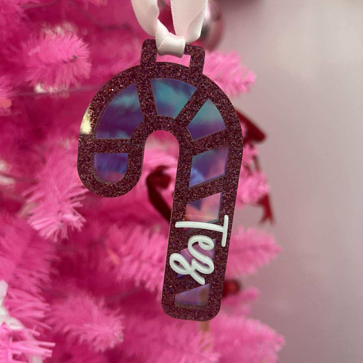 Decorative candy cane ornaments with red glittery finish and light background with name added