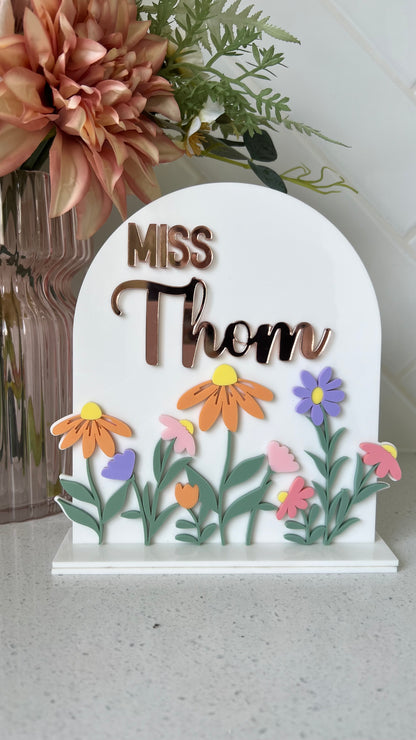 A personalised acrylic desk sign with a floral design and customisable text that reads teachers name 